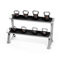 A man holding a dark kettlebell stands in front of a 2 tier kettlebell rack with uk fast delivery
