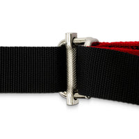 Close-up of a black webbed strap with a silver metal buckle and a red inner layer, shown on a white background.