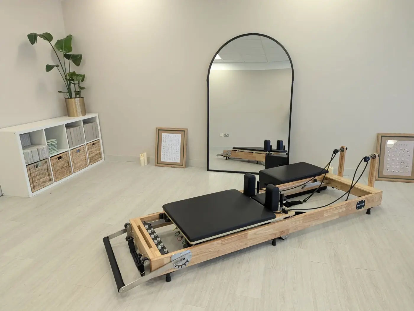 Foldable reformer with light oak wood frame black padded platform and adjustable resistance bands for pilates UK delivery