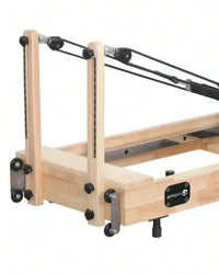 Foldable reformer with light oak wooden frame and black metal parts featuring gymnopro brand plate uk delivery