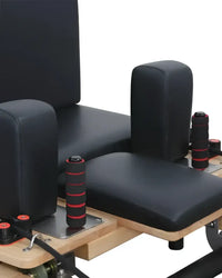 Foldable pilates reformer with black leather upholstery red-accented handles and wooden oak frame uk delivery