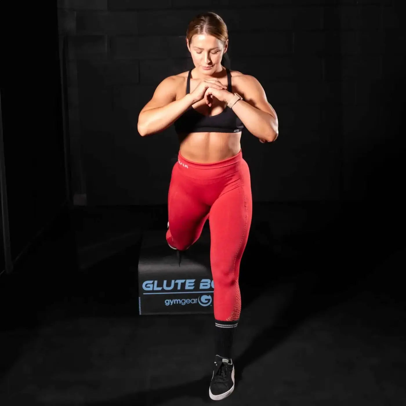 Red athletic leggings with black sports bra and sneakers featuring gymgear logo on waistband for home workout use
