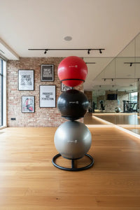 Stacked red black and silver gym balls on a sleek black gym gear gym ball stand for home fitness use