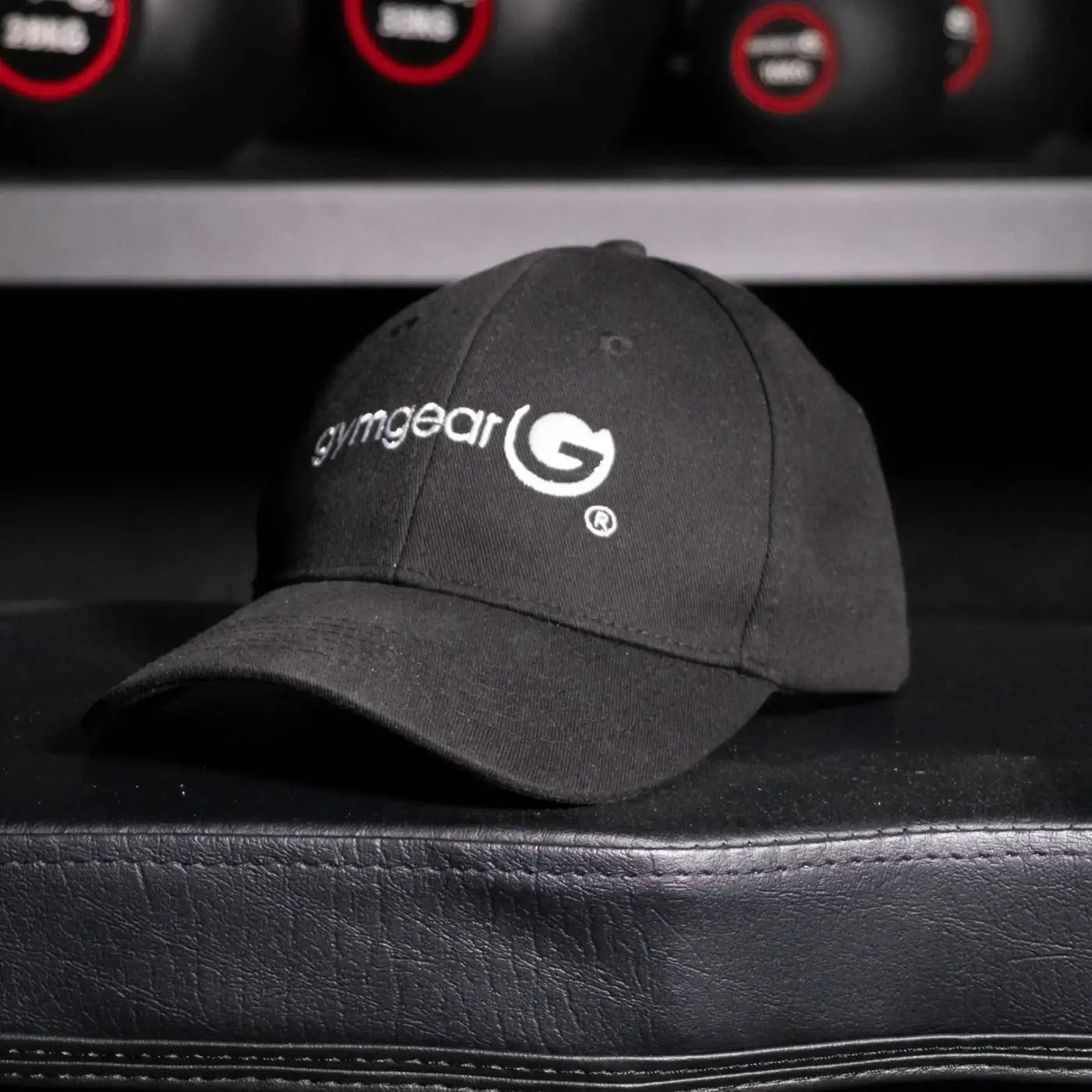 Black gymgear baseball cap with white embroidered logo and brand name on the front panel for athletic use