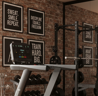 A modern treadmill in a gym setting with a brick wall, motivational posters, weight racks, and wooden flooring.