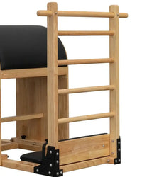 Light-colored wooden pilates reformer with black padded surfaces and metal hardware for space-saving gym gear ladder barrel