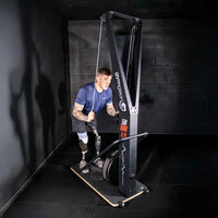 A man using a black gymgear shi trx 2.0 cable machine in a gym setting for home fitness in the UK