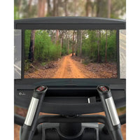 Black Gym Gear X98e cross trainer exercise bike with silver handlebars and digital display showing forest trail