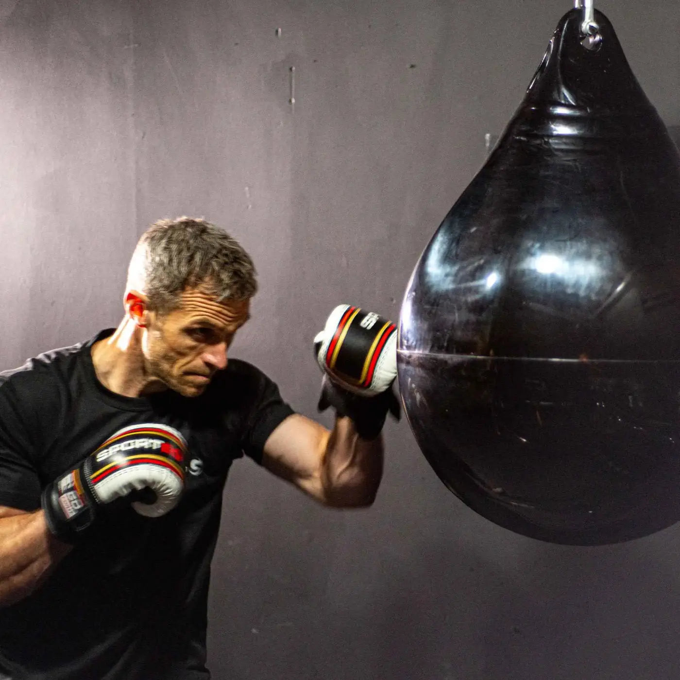 Black punching bag with glossy rubber surface and reinforced stitching part of hiitmax training station for home gyms