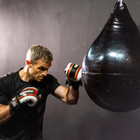 Black punching bag with glossy rubber surface and reinforced stitching part of hiitmax training station for home gyms