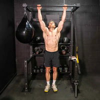 A muscular man performing a pull-up on a black metal HIITMax training station for home gyms