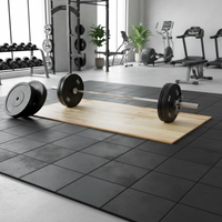 A wooden weightlifting floor mat on a black rubber tile gym floor, with a barbell resting across the center. The background shows a modern gym interior with treadmills, weight racks, and exercise equipment.