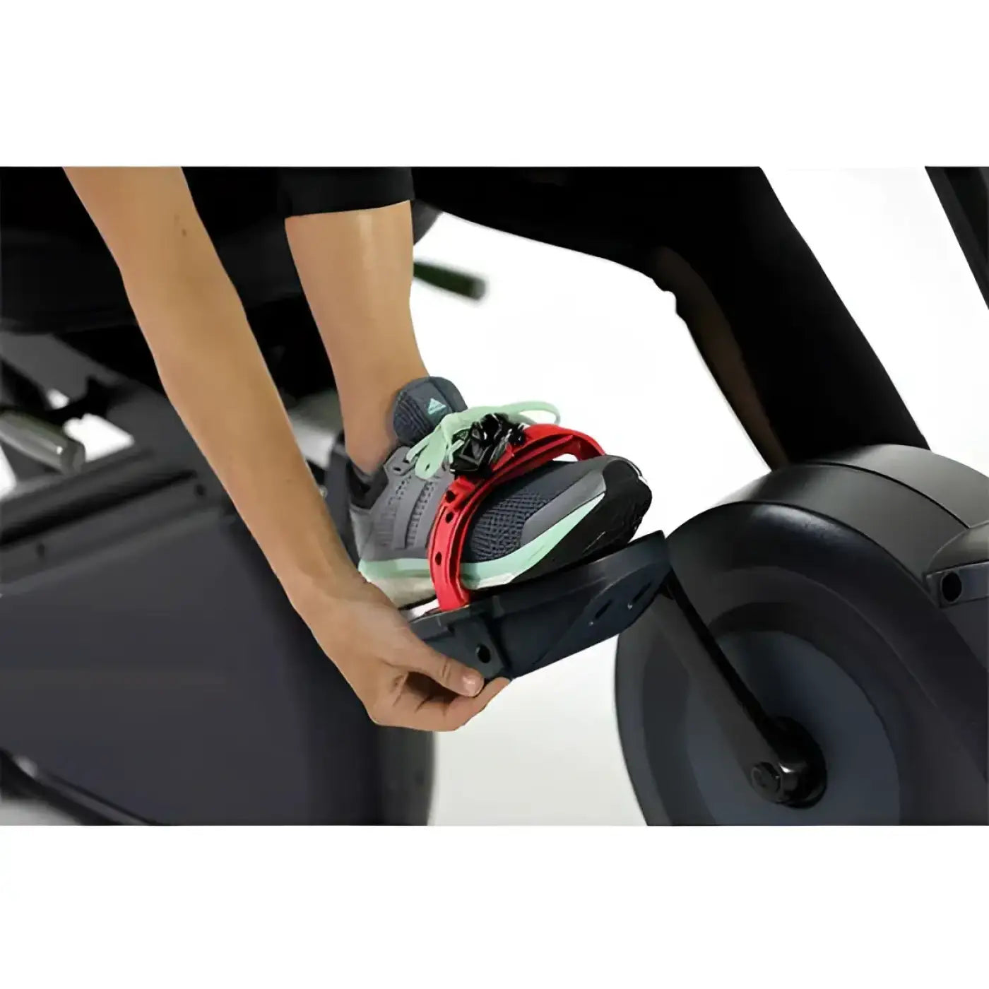Gray and mint athletic shoe with red strap secured to the foot pedal of an r98s sport recumbent bike